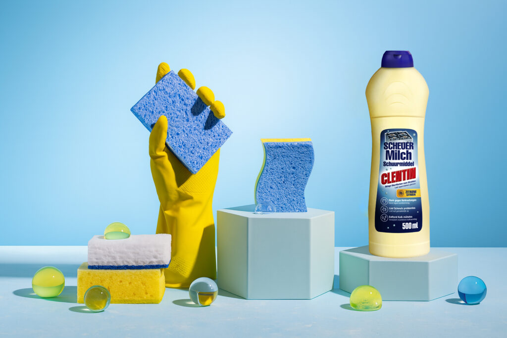 CLENTIN Scheuermilch in neuem Design. Putzhandschuh hält einen Schwamm.